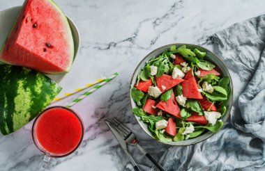 Feta peynirli taze karpuz salatası, roka, ıspanak ve hafif mermer arka planda smoothie ile yeşillikler. Sağlıklı yemek, temiz yemek, Buda kasesi salatası, üst manzara.