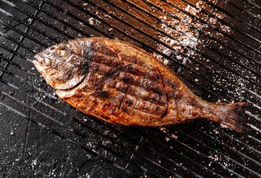 Kömürün üstünde ızgara Dorado balığı, ateş ışığında koyu bir arka plan. Üst görünüm