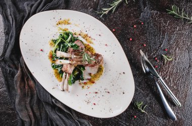 Kavrulmuş baltayla kemiğe biftek, ağır ateşte pişmiş ıspanak ve koyu arkaplanda seramik tabakta sos. Sıcak Et Tabakları, yüksek protein yemeği, üst manzara.