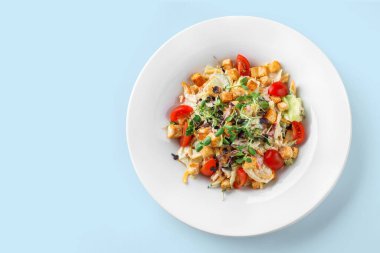 Marullu Sezar salatası, domates, lahana, kızarmış ekmek ve soyutlanmış mavi arka planda sos. Sağlıklı yiyecekler, vejetaryen diyeti, üst manzara.