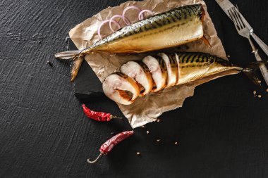 Baharatlı, çatal bıçaklı, biberli, biberli ve ekmekli iştah açıcı kara taş arka planda. Tütsülenmiş uskumrulu sandviç. Akdeniz yemeği, ringa balığı, deniz ürünleri, üst manzara.