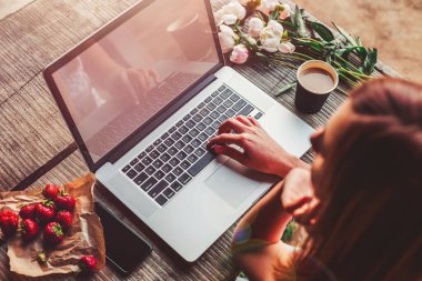 Çalışma alanı kız eli, dizüstü bilgisayar, şakayık çiçeği buketi, kahve, çilek, ahşap masada akıllı telefon. Açık hava parkında çalışan serbest çalışan biri. Üst kat ofis masası. Düz yatıyordu