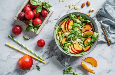 Şeftalili, ıspanaklı, mikro yeşillikli, erikli, beyaz peynirli ve bademli taze yaz salatası. Sağlıklı yemek, temiz yemek, Buda kasesi salatası, üst manzara.