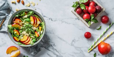 Şeftalili taze yaz salatası, ıspanak, mikro yeşiller, açık mermer arka planda beyaz peynir ve badem. Sağlıklı yemek, temiz yemek, Buda kasesi salatası, üst manzara.