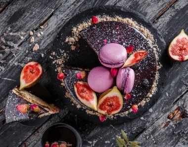 Aynalı kremalı çikolatalı pasta. Makaronlarla, incirlerle, koyu kırsal arka planda çiçeklerle süslenmiş. Tatil pastası kutlaması. Üst manzara, düz uzanma