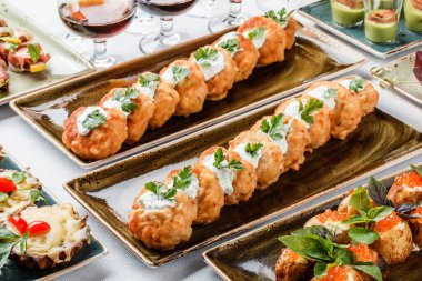 Lezzetli aperatifler, bol yağda kızartılmış et soslu ve tabakta otlar, ziyafet masasında. Yemek servisi, kanepe ve atıştırmalıklar, yakın çekim.