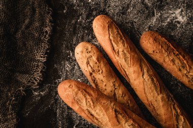 Siyah arkaplanda unlu taze ekmek baget ekmeği. Pasta ve fırın, gıda konsepti, üst manzara.