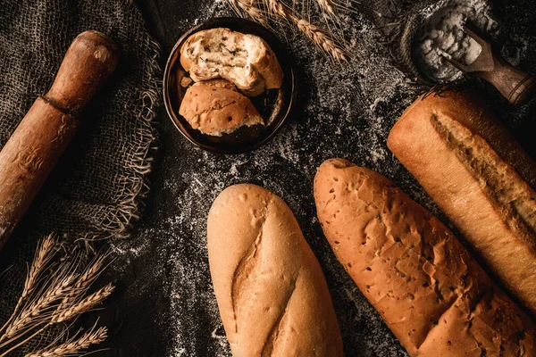 Rozbité Chlebové Bagety Černém Břidlicovém Pozadí Pšeničnými Hřeby Pytlovinou Moukou — Stock fotografie