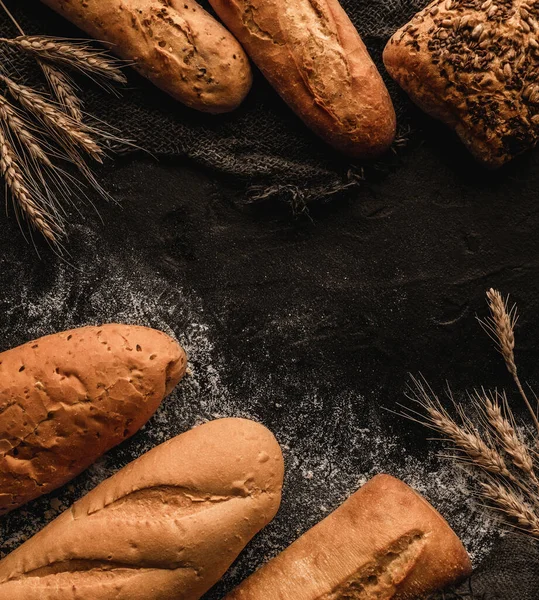 Různé Chutné Chleby Buchty Tmavém Břidlicovém Pozadí Pšeničnými Hroty Pytlovina — Stock fotografie