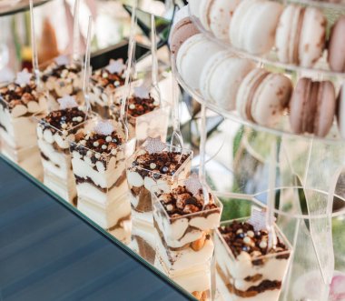 Düğün tatlısı, kurabiyeler, pastalar, kekler, kekler, pastalar ve çiçeklerle dolu tatil arkaplanda tatlılık. Şeker çubuğu