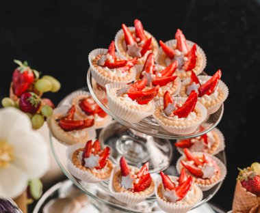 Çilekli meyveli tart ve krema, pastalar ve çiçeklerle tatil arka planında tatlılık. Lezzetli tatlı ve çikolata.