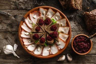 Çavdar ekmeğiyle dilimlenmiş tuzlu domuz yağı ve pastırma, yabanturpu, rustik ahşap arka planda tabakta baharatlar. Aperatif, üst görünüm