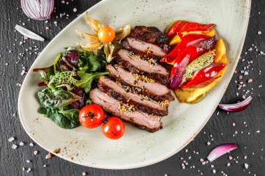 Koyu taştan arka planda salata ve sebzeli ızgara dana biftek. Sıcak Et Tabakları, üst görünüm