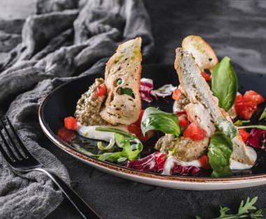 Sağlıklı ızgara patlıcan salatası, roka, ıspanak, domates, kızarmış ekmek ve gri arka planda seramik bir tabakta sos. Sağlıklı vejetaryen yemekleri, temiz yemek, diyet, yakın çekim.