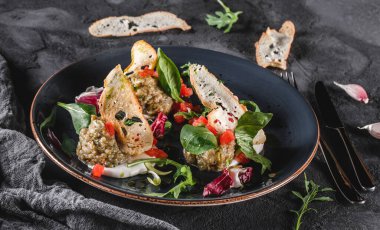 Sağlıklı ızgara patlıcan salatası, roka, ıspanak, domates, kızarmış ekmek ve gri arka planda seramik bir tabakta sos. Sağlıklı vejetaryen yemekleri, temiz yemek, diyet, yakın çekim.