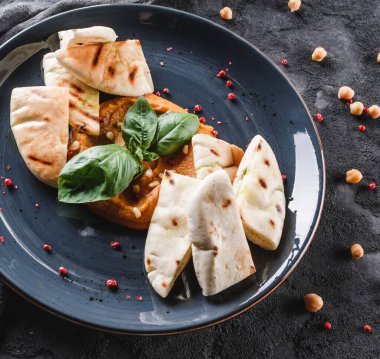 Gri arka planda seramik tabakta zeytinyağı, paprika, çam fıstığı ve pita ekmeği ile nohut. Sağlıklı vejetaryen yemekleri, temiz yemek, perhiz, üst manzara.