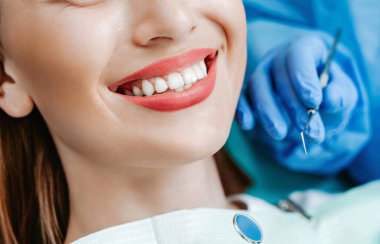 Diş sağlığı kliniğinde beyaz dişli çekici bir genç kadın. Tıbbi aletlerle el doktoru diş hekimi. Sağlıklı diş konsepti