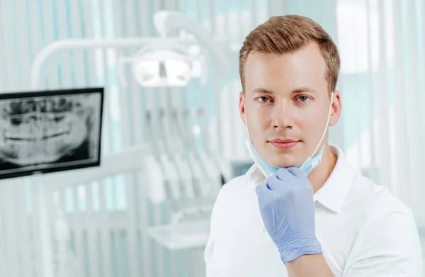 Doctor dentist smiling without medical mask in dental clinic on light background with medical equipment, x-ray dental. Smile healthy teeth concept