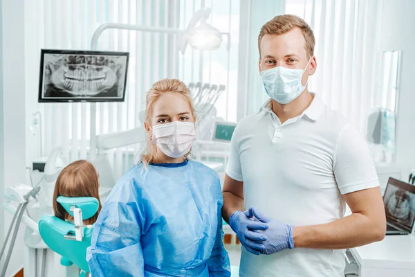 Two doctor dentist in medical masks and gloves work in dental clinic on backdrop with medical equipment, x-ray dental and patient. Smile healthy teeth concept