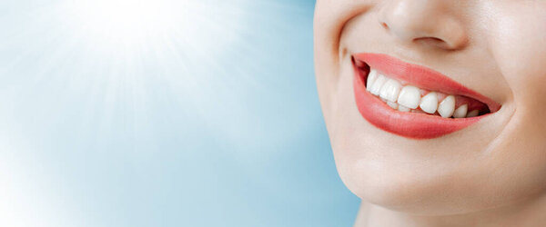 Smiling female mouth with natural white teeth in light blue background in dental clinic. Smile healthy teeth concept, wide composition