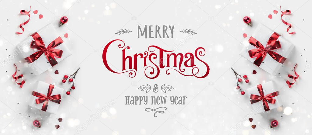 Merry Christmas and New Year text on white background with gift boxes, ribbons, red decoration, bokeh, sparkles and confetti. Xmas greeting card, bokeh, light. Flat lay, top view