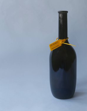 Fotokopi alanı olan gri-mavi arkaplanda kargo mührü olan şarap şişesi.