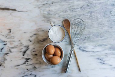 Mermer bir masada yumurta, şeker ve yemek takımı
