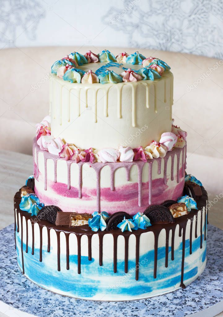 Three-tiered colored cake with colored smudges of chocolate on a light background. Picture for a menu or a confectionery catalog with copy space