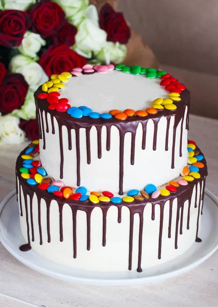 White Birthday cake with colorful Sprinkles over a light background with a bouquet of roses — Stock Photo, Image