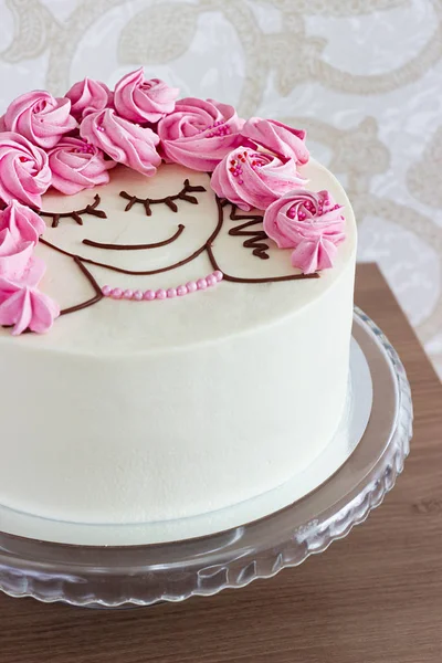 Gâteau festif avec des fleurs de meringue et un visage de fille sur un fond clair — Photo