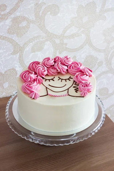 Festive cake with flowers from meringue and a girl face on a light background
