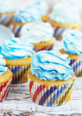 beyaz ahşap arka plan üzerinde krem kapağı mavi cupcakes