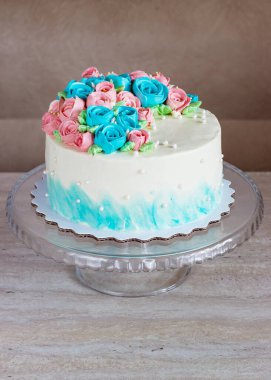 Hafif ahşap arka planda tereyağlı kremadan yapılma parlak güllerle kaplı muhteşem bir pasta.