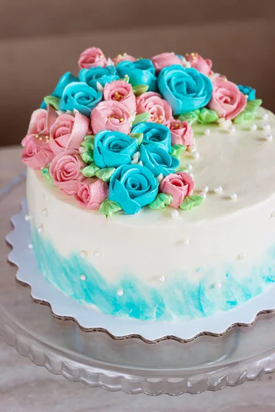 Underbar tårta täckt av ljusa rosor gjorda av smör grädde glasyr på ljus trä bakgrund — Stockfoto