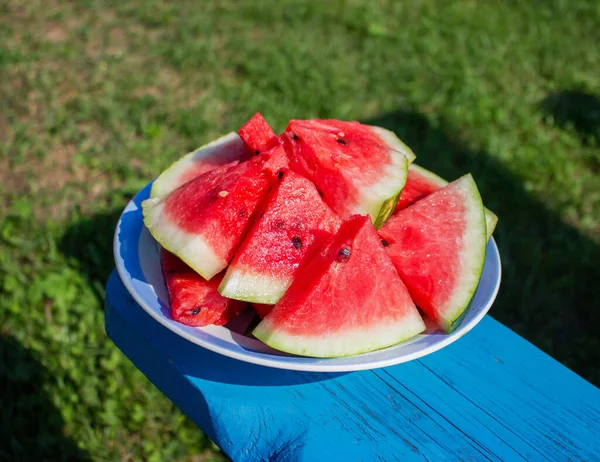 Schijfjes rijpe watermeloen op een bord in de tuin — Stockfoto