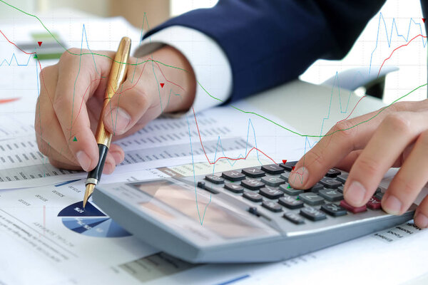 Business concept,Hand using calculator and hold pen pointing at the graph.The image has a striped graph.