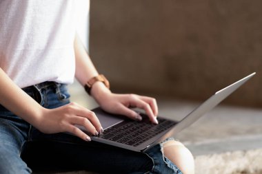 Genç kadınlar bacak dizüstü bilgisayar kullanarak. O çimento yere oturdu.