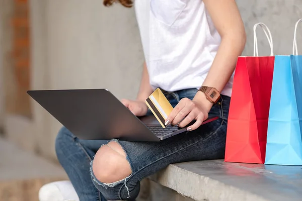 ショッピングの女の子は 手でクレジット カードを保持します 彼女はノート パソコンを使用してセメントの床に座ってください — ストック写真
