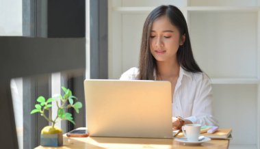 Kız bilgisayarı modern bir ofiste rahat bir şekilde kullanıyor..