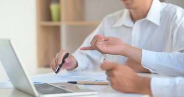 İki genç adam fikir alışverişinde bulundu. Grafikte bir kalem ve bir dizüstü bilgisayarla..