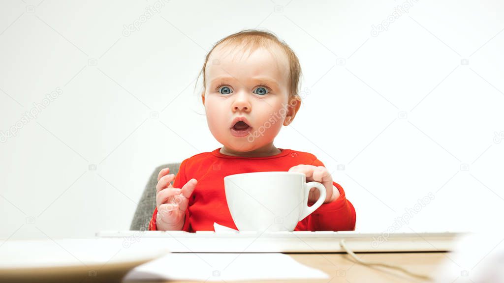 What Surprised child baby girl sitting with keyboard of modern computer or laptop in white studio background. early development of modern kids concept. Businesswoman, lady boss and girl-boss concepts