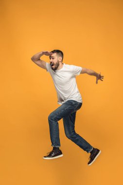 Hareketli bir özgürlük. yakışıklı genç adam karşı turuncu arka plan atlama