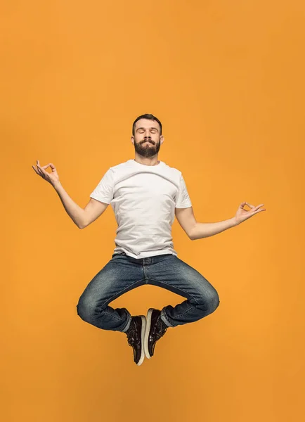 Свобода передвижения. Красивый молодой человек прыгает на оранжевом фоне — стоковое фото