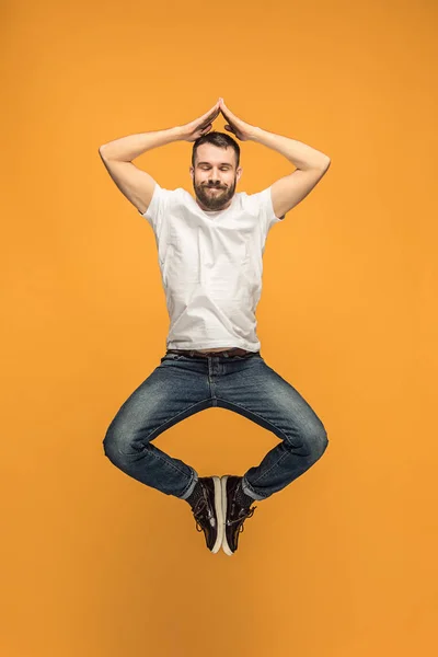 Freiheit in der Bewegung. schöner junger Mann springt vor orangefarbenem Hintergrund — Stockfoto