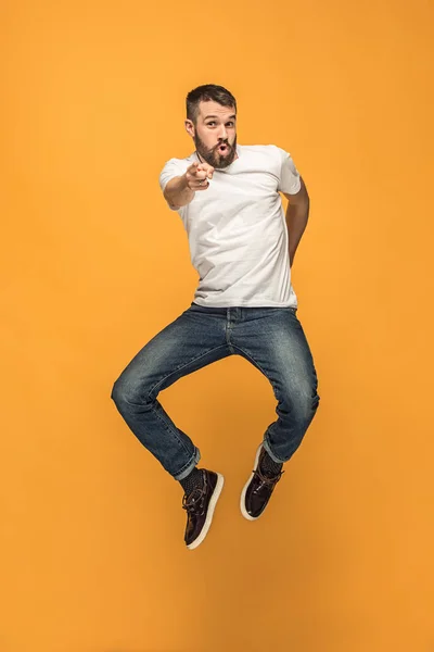 Liberdade em movimento. jovem bonito pulando contra fundo laranja — Fotografia de Stock