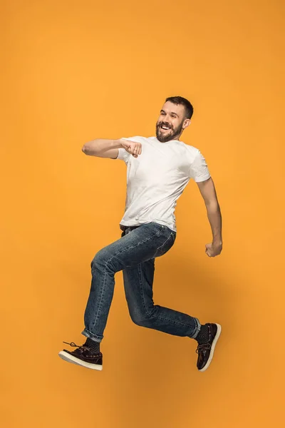 Vrijheid in beweging. knappe jongeman springen tegen oranje achtergrond — Stockfoto