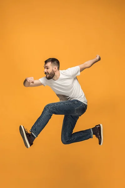 Frihet i rörelse. stilig ung man hoppa mot orange bakgrund — Stockfoto