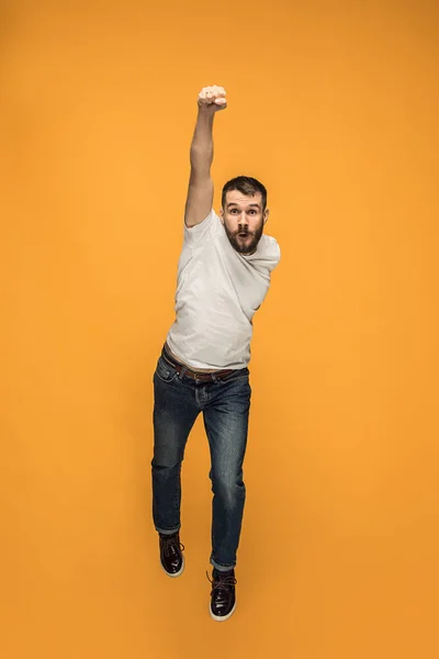 Vrijheid in beweging. knappe jongeman springen tegen oranje achtergrond — Stockfoto