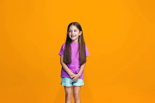 La chica adolescente feliz de pie y sonriendo contra el fondo naranja . — Foto de Stock