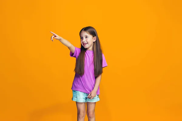 あなたは、オレンジ色の背景にポートレート、クローズ アップの長さの半分を指している幸せの十代の少女. — ストック写真